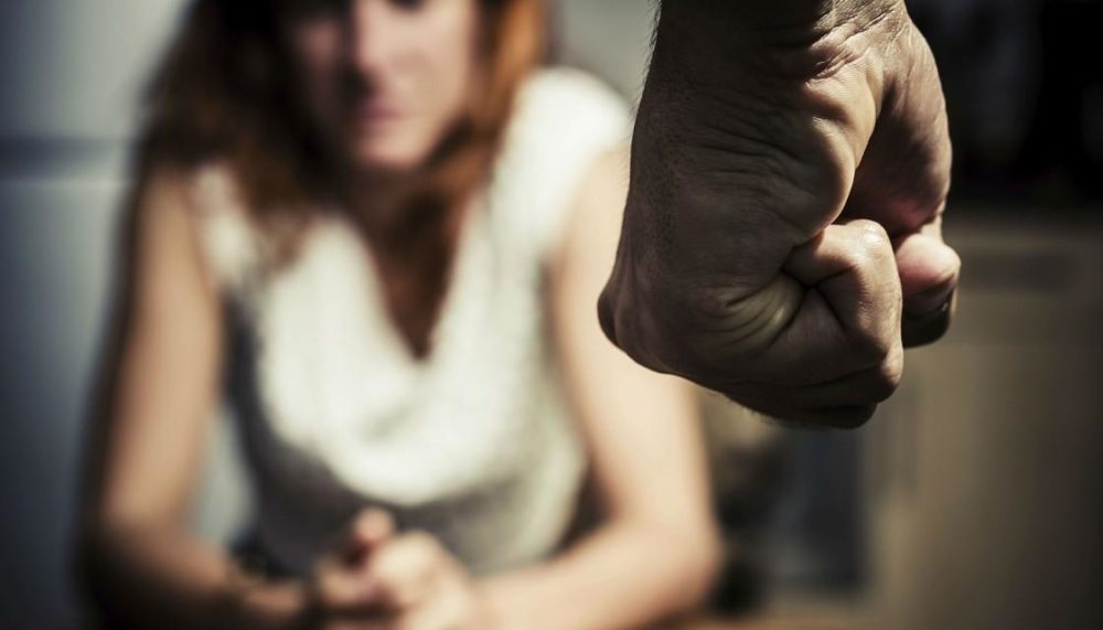 Clenched fist threatens woman sitting down