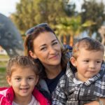 Happy family outdoors. Mom with two toddlers.