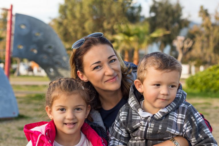 Happy family outdoors. Mom with two toddlers.