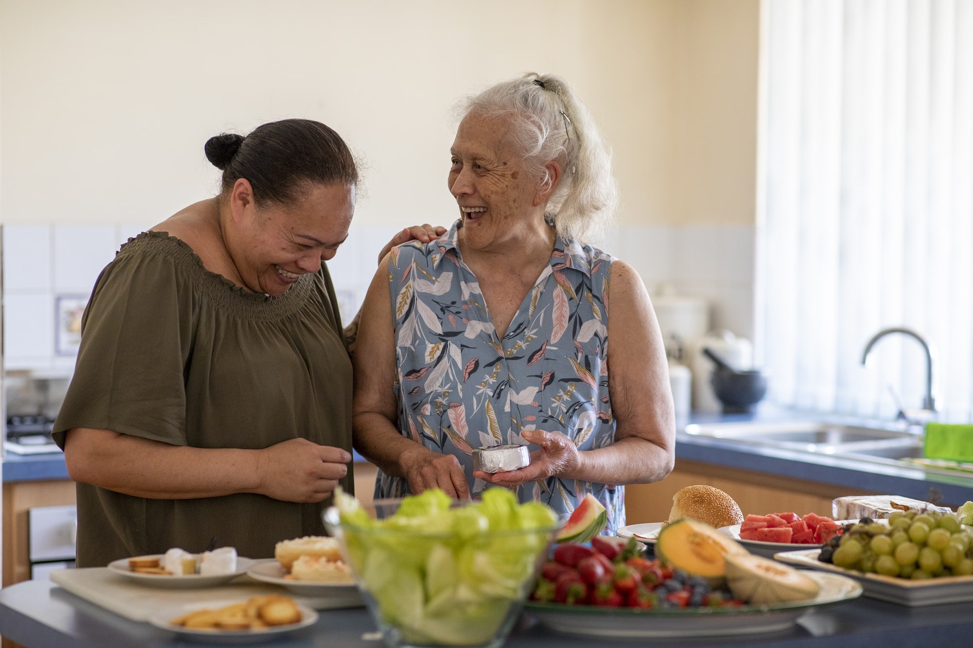 Senior Pacific Islander woman and her mature daughter preparing food together in their kitchen at home.