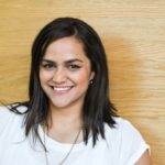 Happy, young, Maori female wIth shoulder length dstk haIr in busIness attIre on her own and against a wooden background