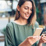 Young woman shopping online in cafe using smartphone and credit card