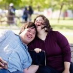Couple in love of 26 years old Down Syndrome in a park in Montreal doing selfie with mobile phone. They are learning to live independently. Color and horizontal photo was taken in Quebec Canada.