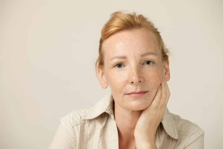 Studio portrait of woman blondes with freckles on beige background