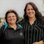 Two women standing together one with arm around shoulder