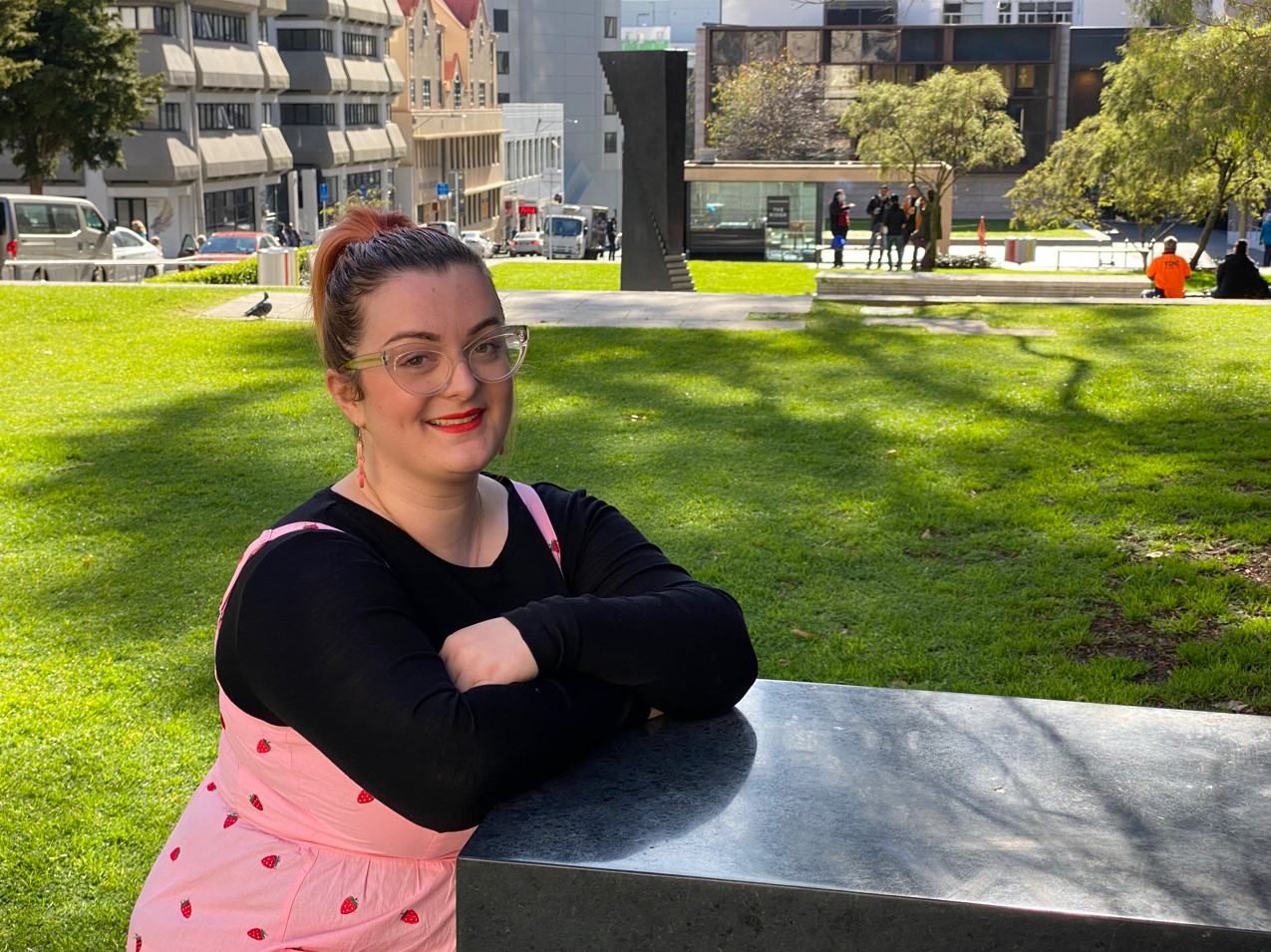 Hayley Tinning sat outside smiling on bench in sun