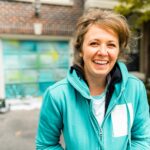 Female mural artist creating art on the garage door of the private home in the city.